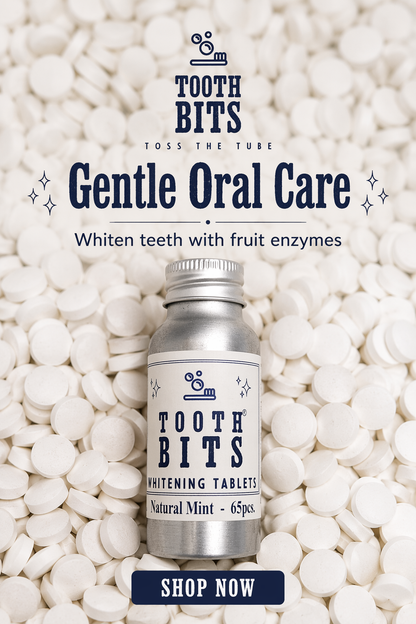 A bottle of Tooth Bits Gentle Oral Care whitening tablets sits on top of a bed of white tablets. The bottle is silver with a white label featuring navy blue text.