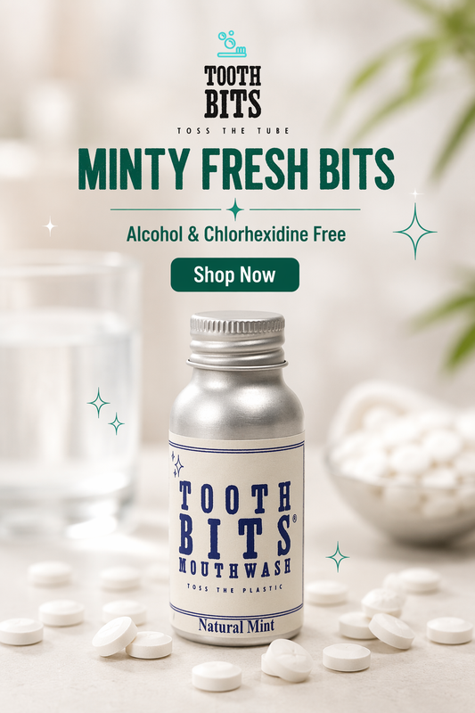 A bottle of Tooth Bits Mouthwash labeled Natural Mint, surrounded by white mouthwash tablets on a light surface, with a glass and bowl of tablets blurred in the background. Prominent text reads 'TOOTH BITS', 'MINTY FRESH BITS', 'Alcohol & Chlorhexidine Free', and 'Shop Now'.