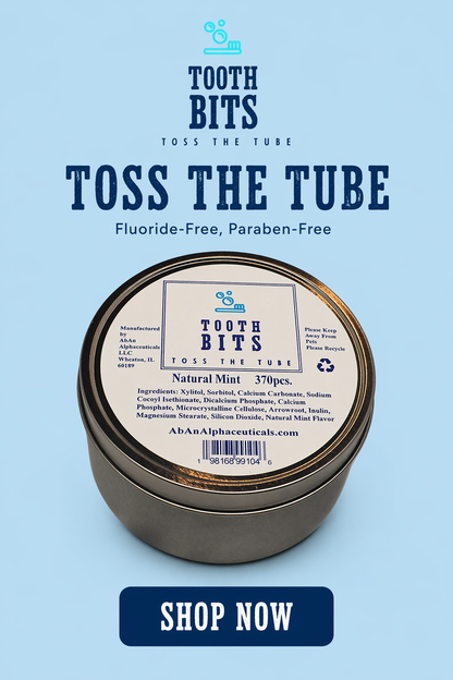 A round metal tin of Tooth Bits 'Toss the Tube' Natural Mint toothpaste on a light blue background with promotional text reading 'TOOTH BITS TOSH THE TUBE' and a dark blue 'SHOP NOW' button.